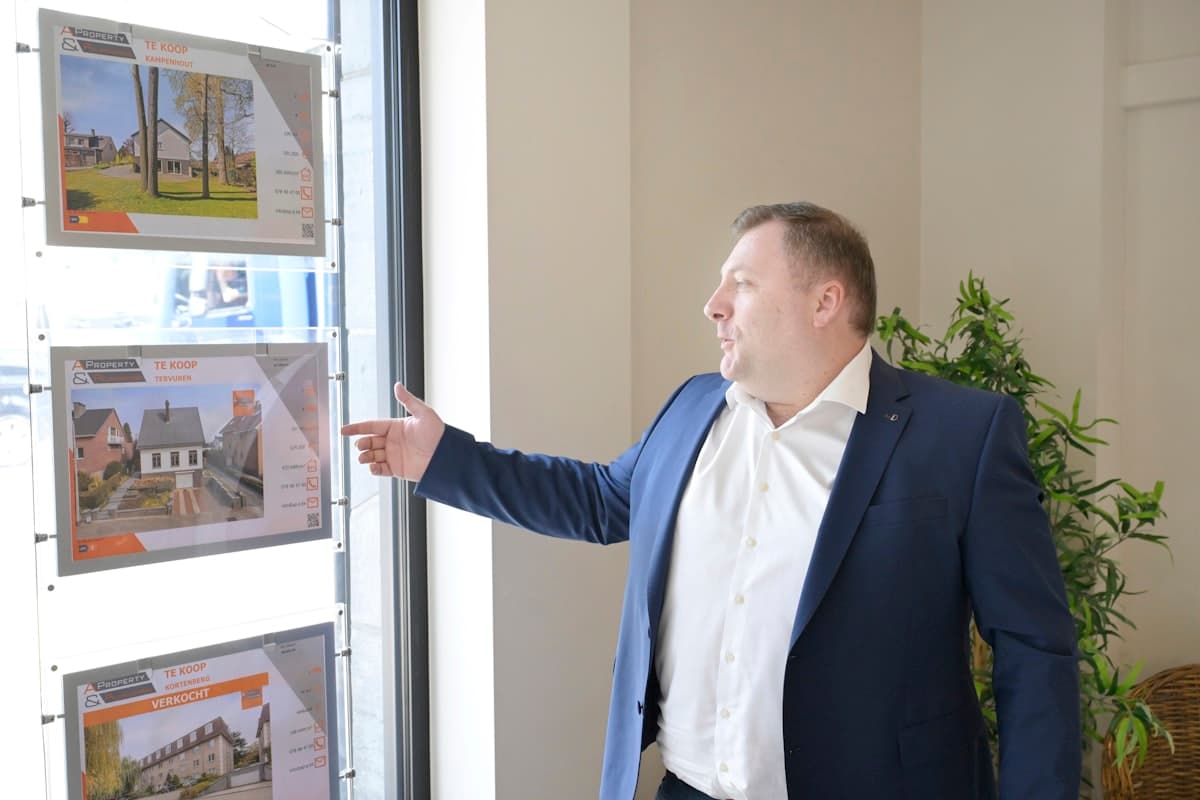 Real estate agent standing in front of a property listings window display