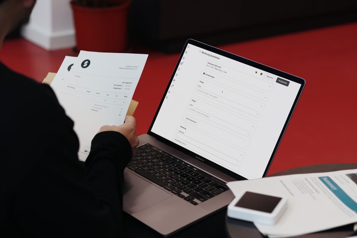 Business owner at a desk reviewing financial paperwork and laptop