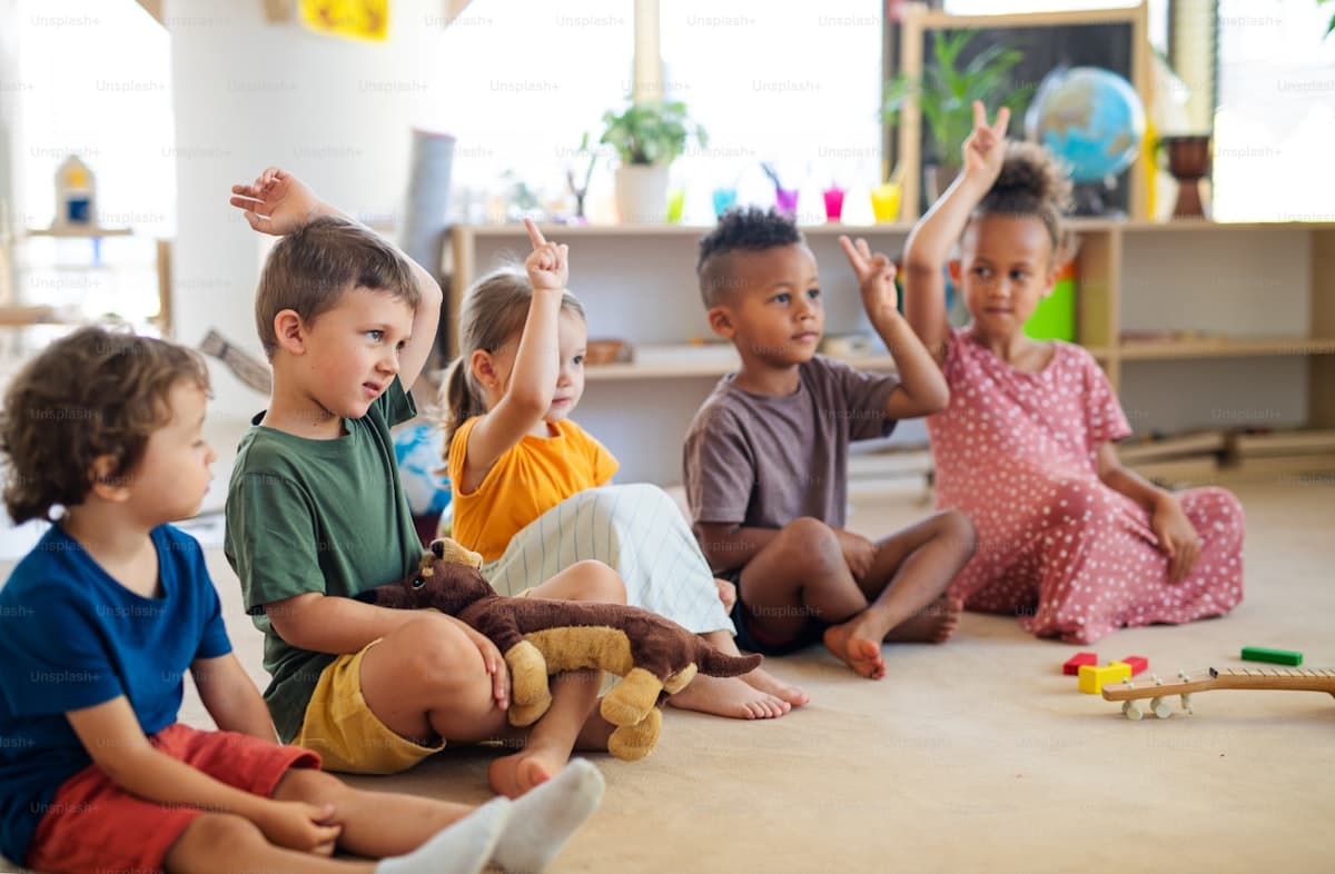 Young children raising hands in a bright childcare classroom
