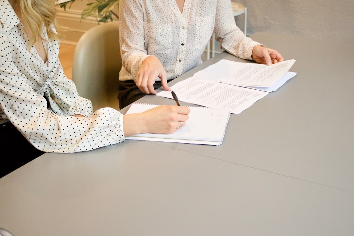 Two women reviewing and signing loan documents at a consultation desk