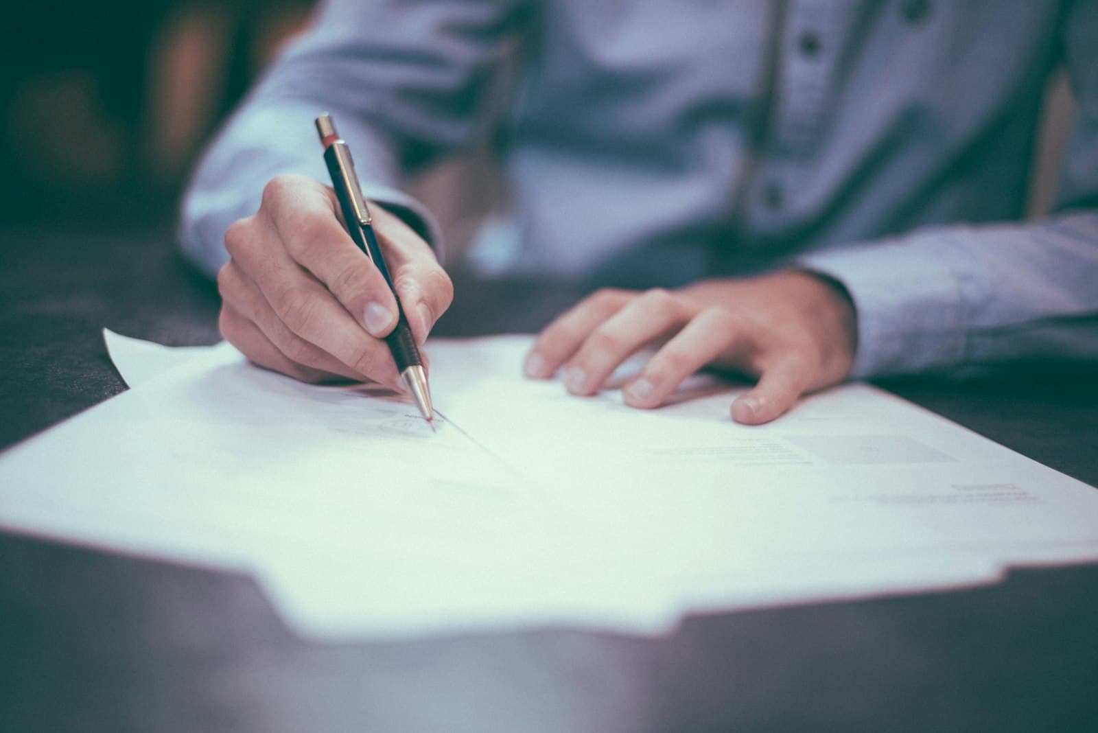 Mortgage broker signing client documents at a desk
